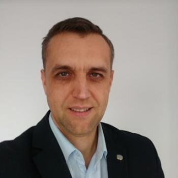 close up photo of man in suit standing in front of white background 