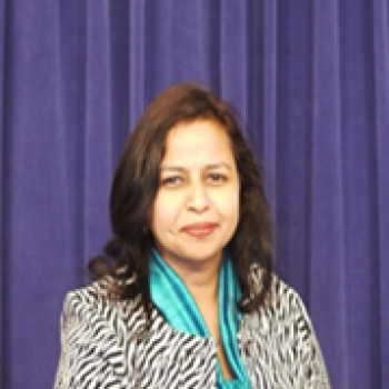 women with blue scarf stands in front of purple background 