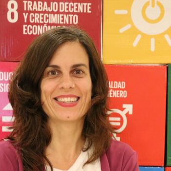 woman with brown hair standing in front of colourful background 