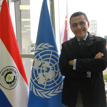 man stands by UN and Paraguayan flag 