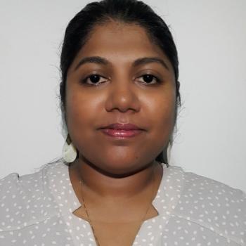 woman with dark hair and white shirt looks into the camera 