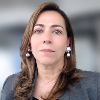 A woman in a grey suite against a blurred background