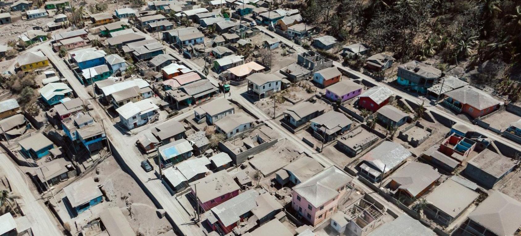 An aerial shot of buildings and houses covered by thick grey soot and smoke.