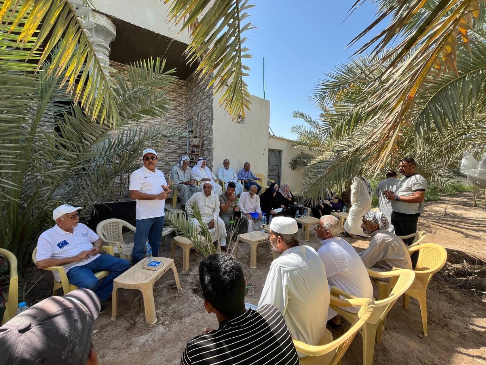 A group of men are outdoors learning from one man standing in the middle of the circle 