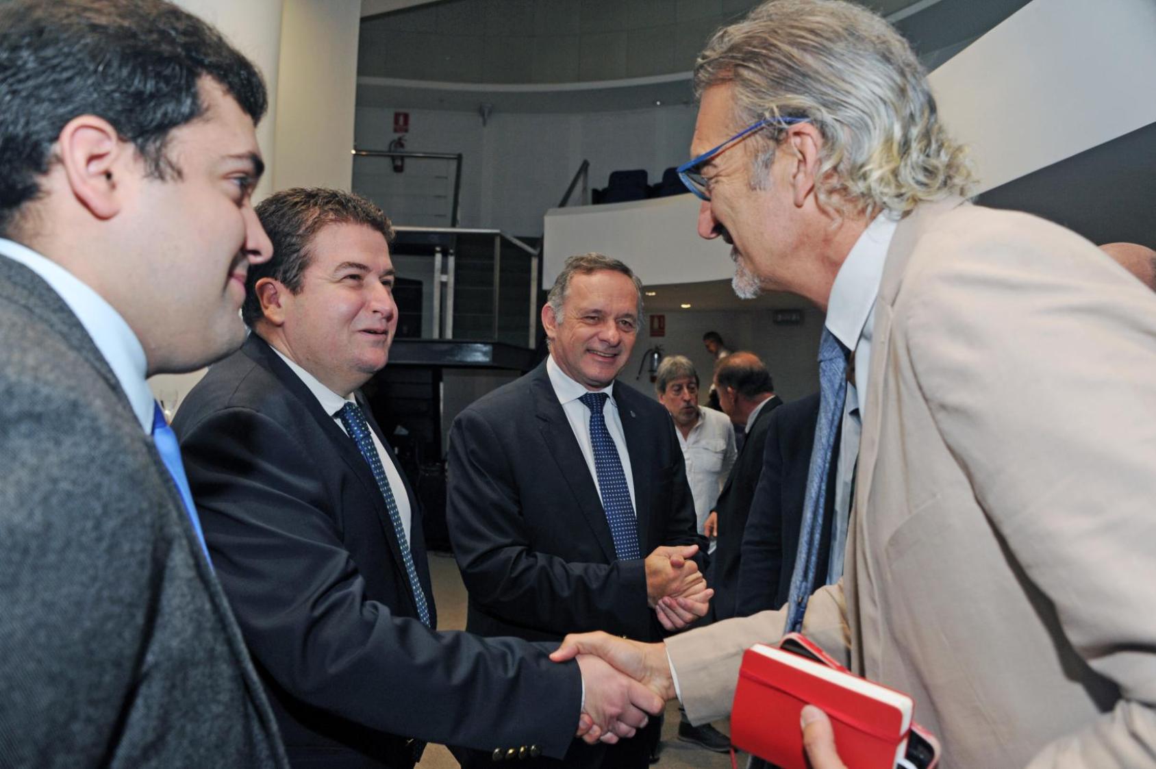 Three men shake hands prior to a discussion