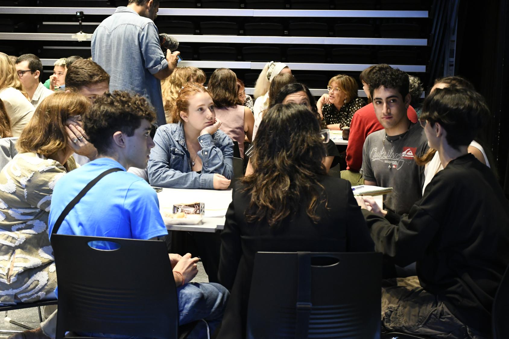 A group of young people seated at a table and engaging in a discussion