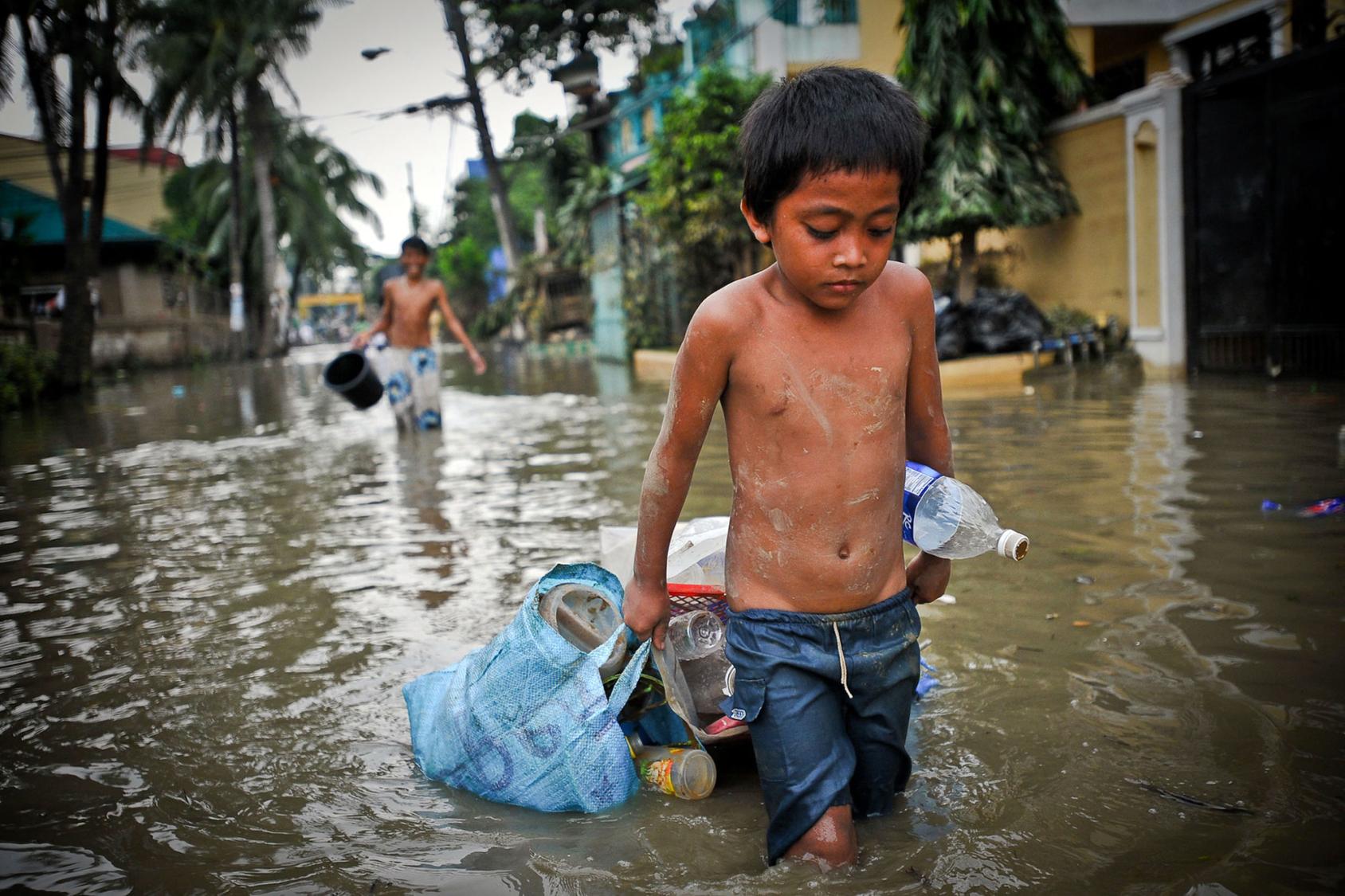 A boy drags possessions through the flooded streets of Manila in the aftermath of a typhoon.