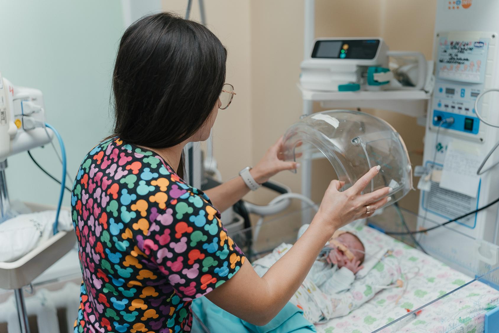 A woman is taking care of a little baby in an incubator 