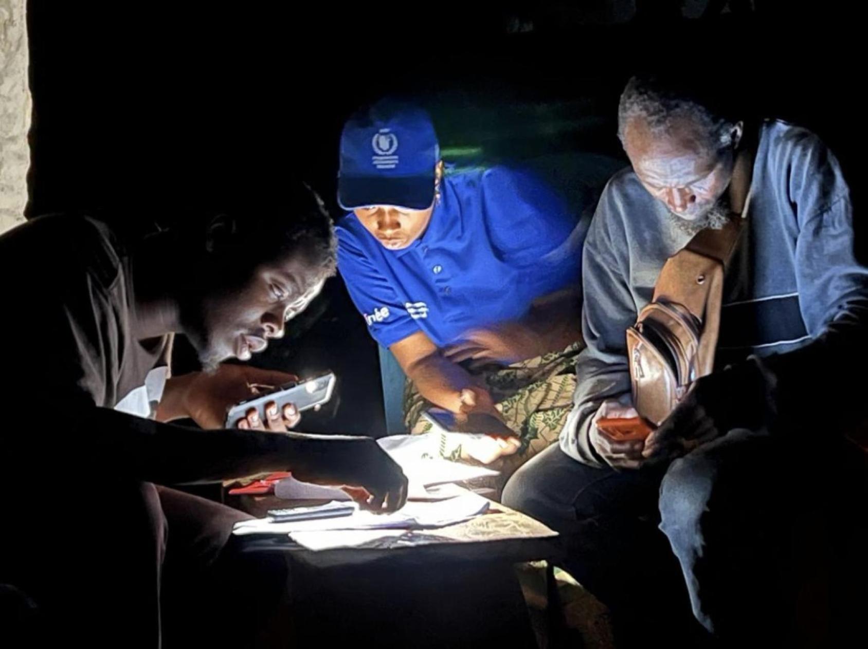 People reading a document with the light of a mobile phone