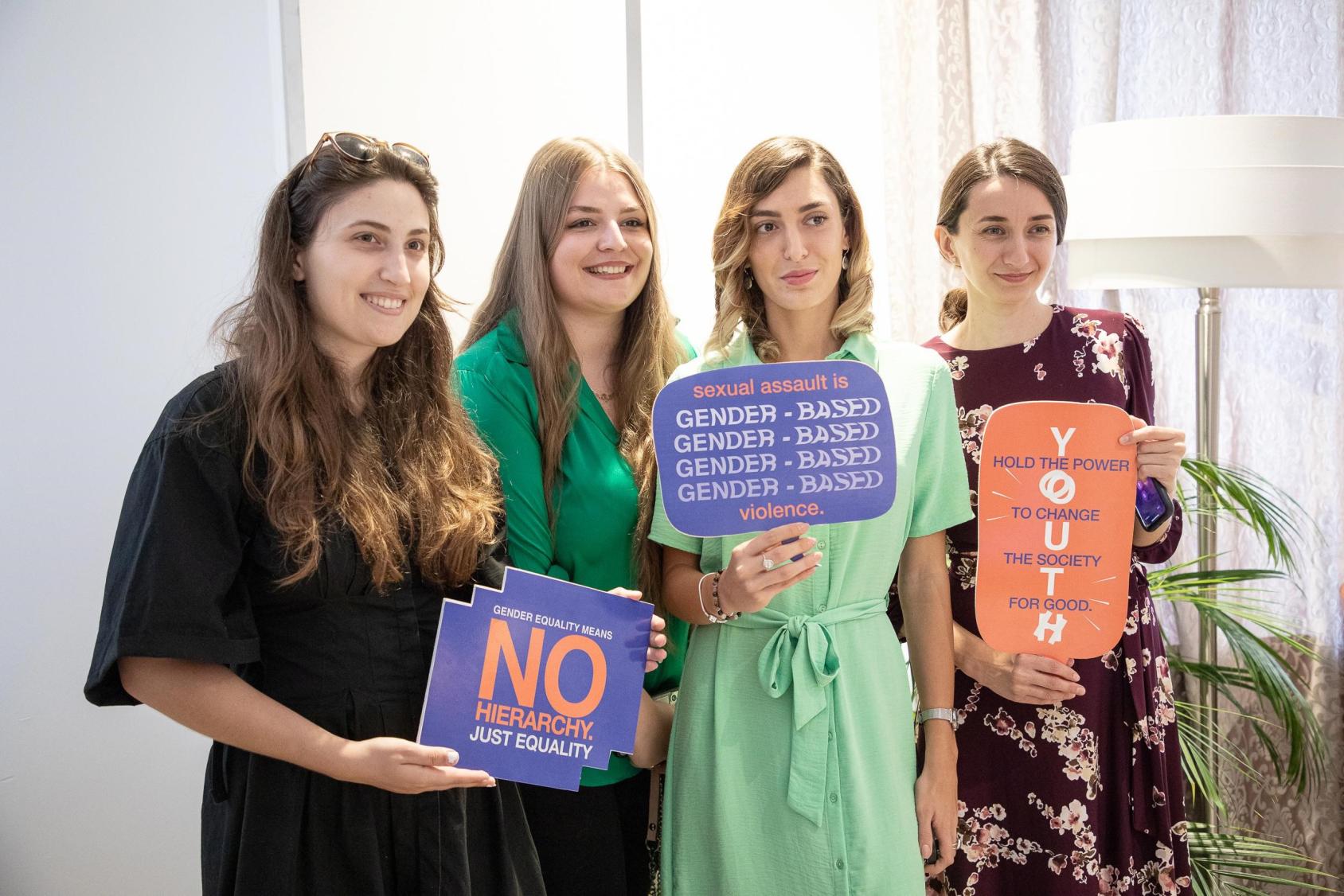 A group of young girls holding up signs about combating violence against women