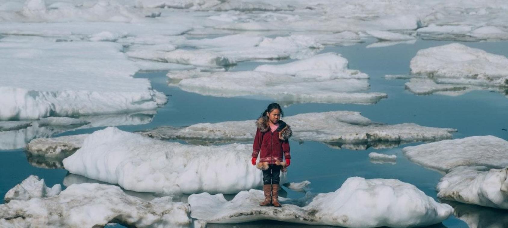 A little girl standing between ice blocks in a body of water