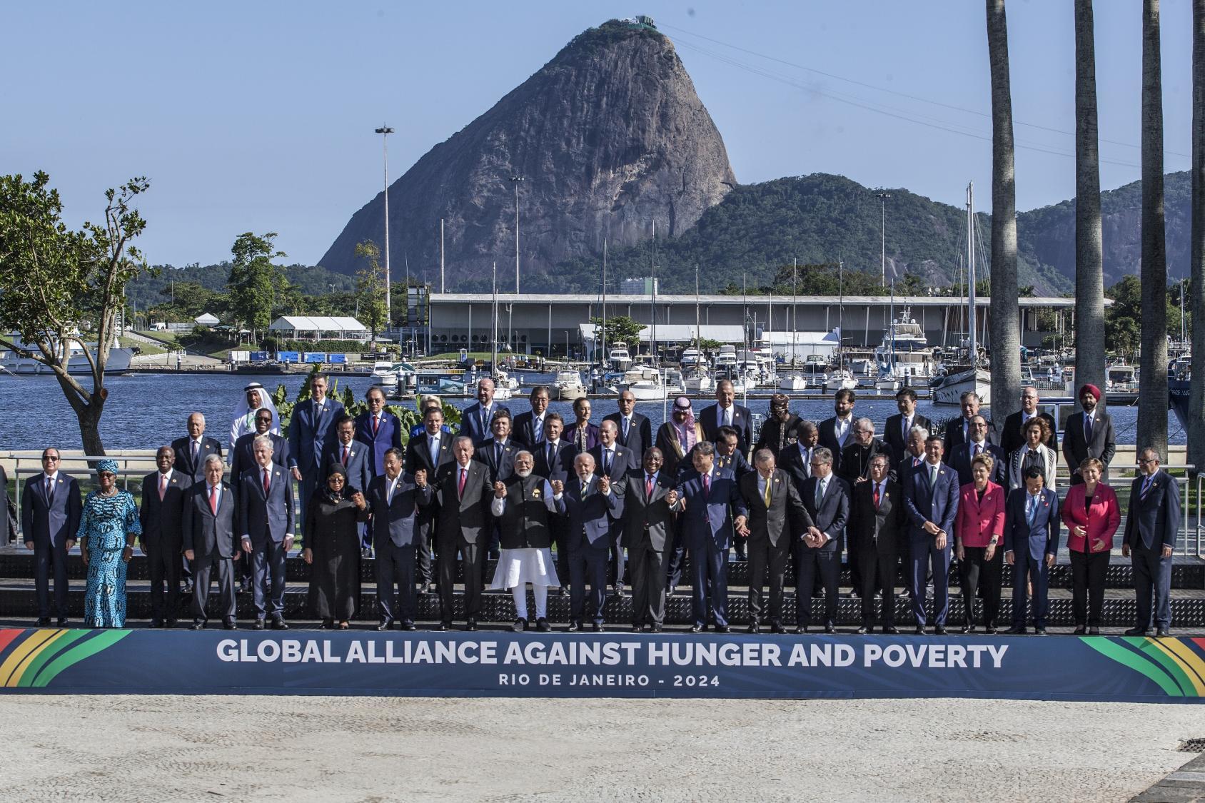 A large group of people from the G20 gathered in an outdoor space with the G20 signage in the background