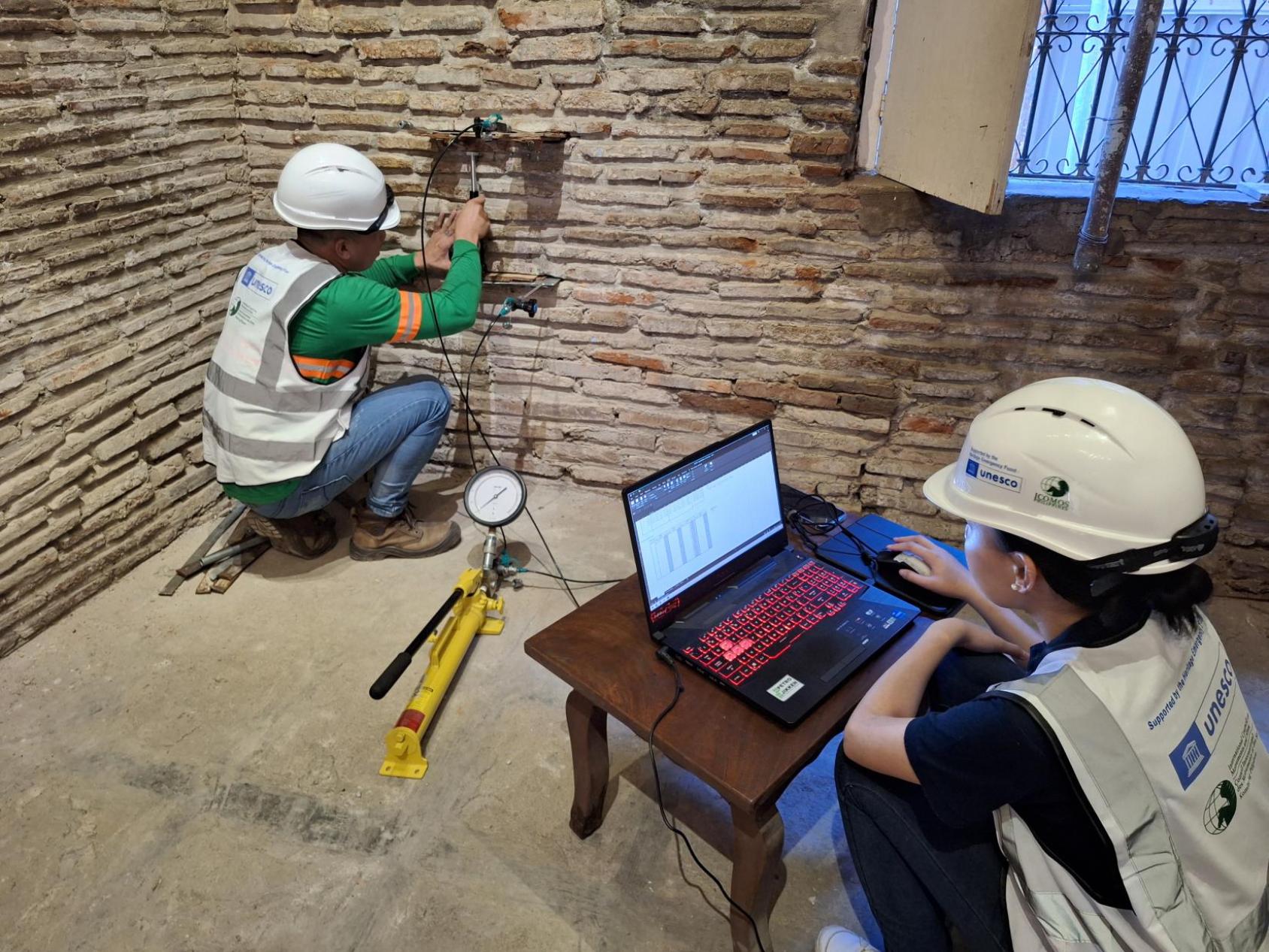 A group of people wearing UNESCO attire are in a room with computers