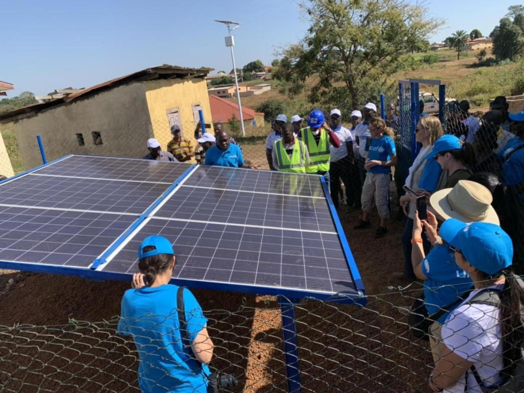 A group of people are outdoors around solar panels