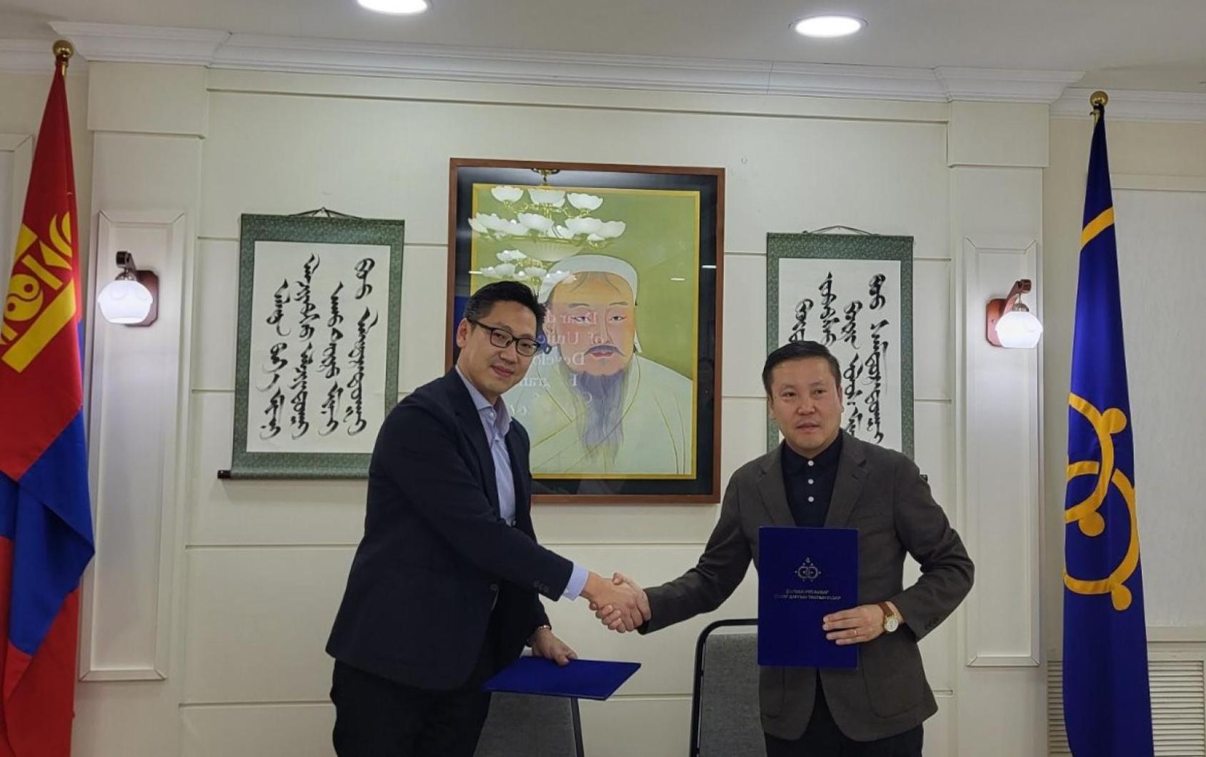 Two people shake hands after signing a document on e-services