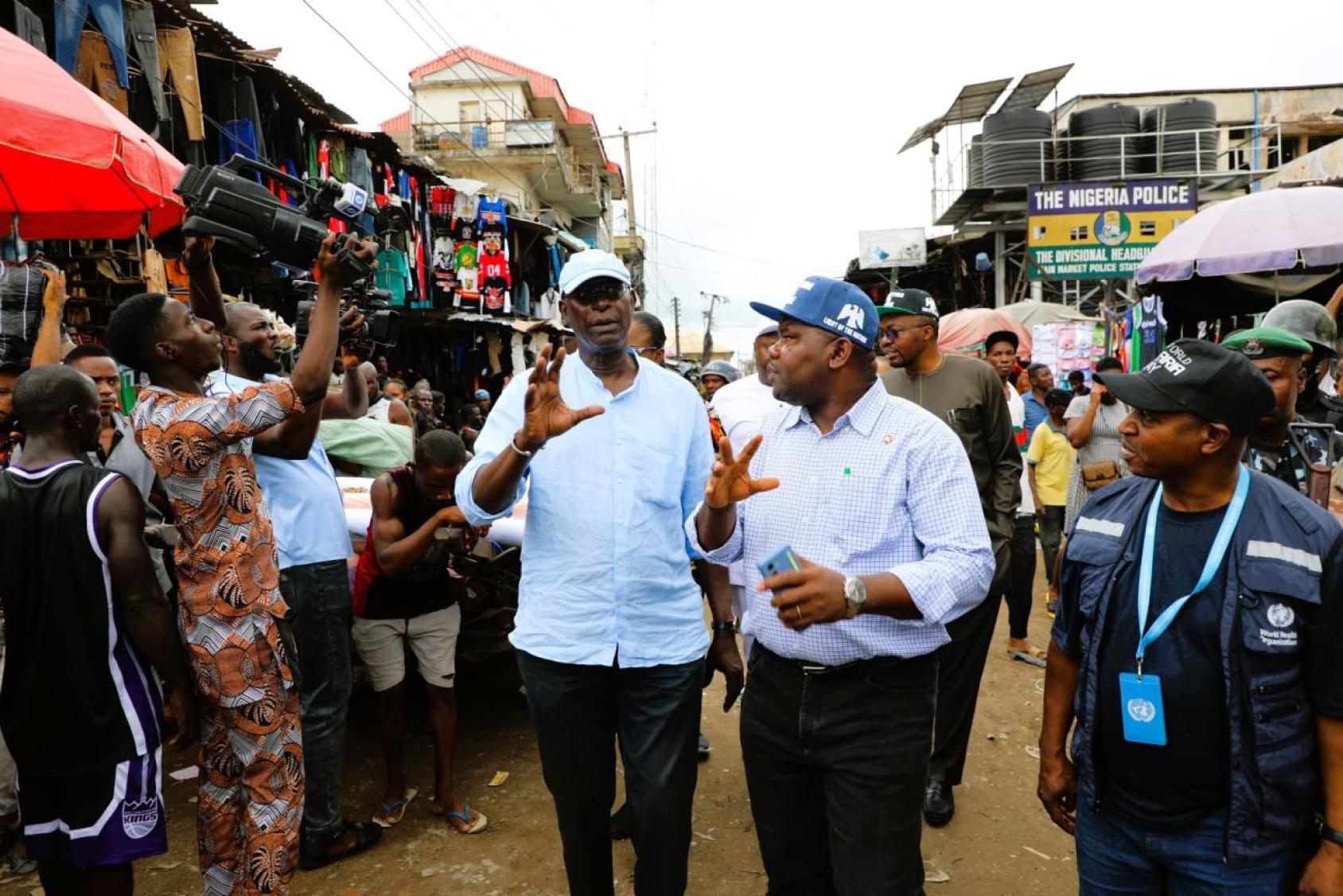 Two men are walking through a crowd of people in a rural area