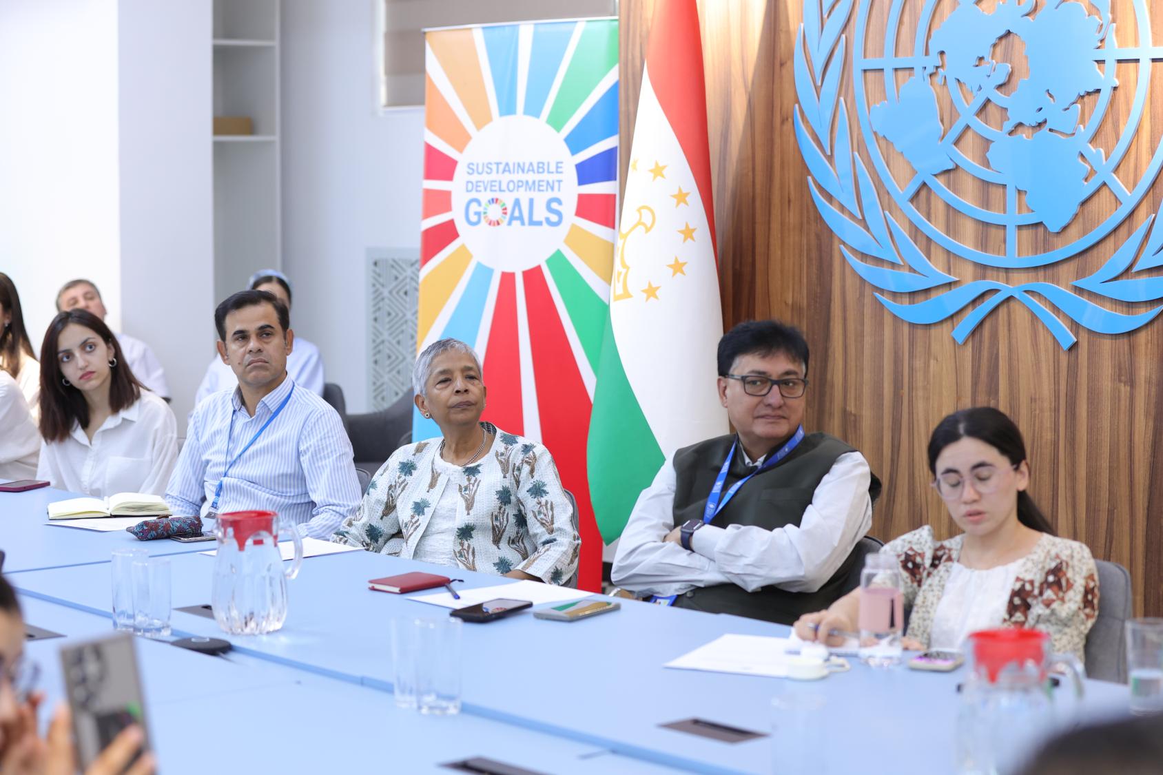 a group of people in listening seated in front of a background with UN logos