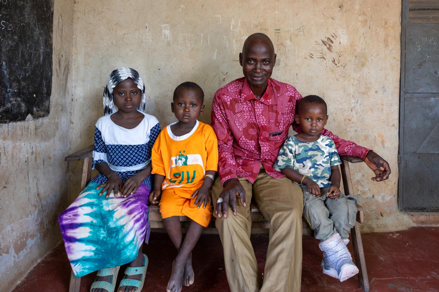 A man is seated outside with his three children