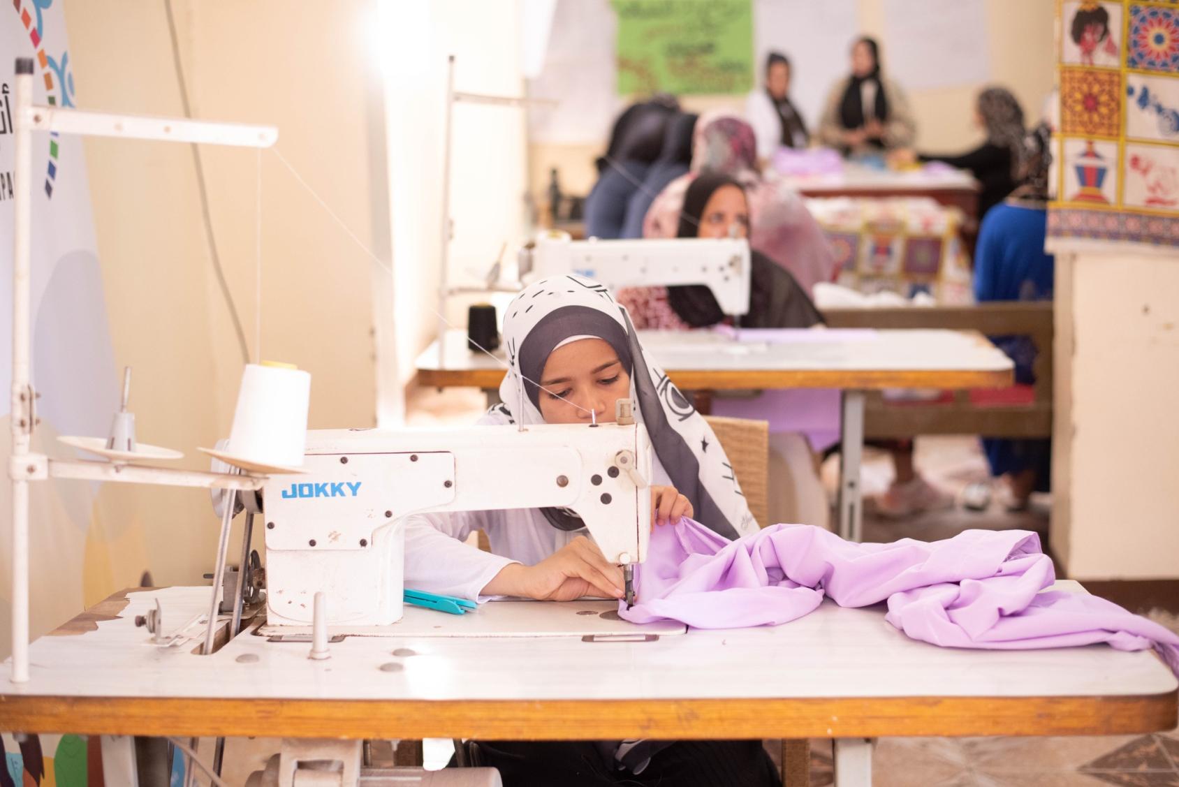 A woman is seated at a sewing machine