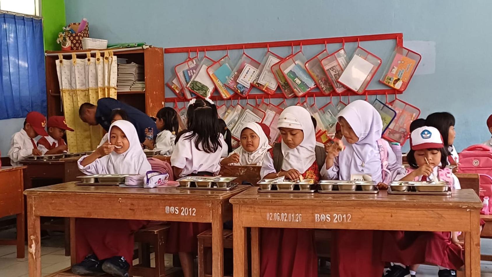A group of children seated at a table and eating their food 