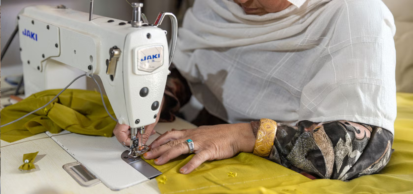 A close up of a woman's hands next to a sewing machine
