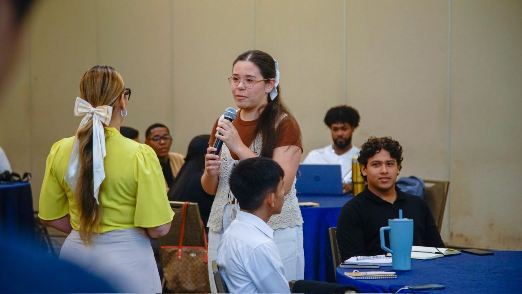 A young woman holds a microphone amidst her vocational training.