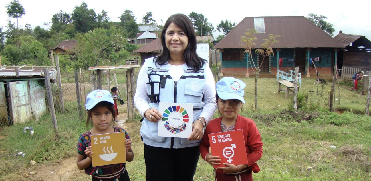 A woman holds a sign with two children.