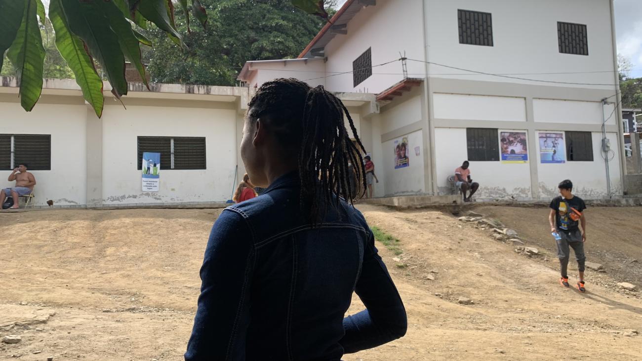 The silhouette of a young girl near a white building. 