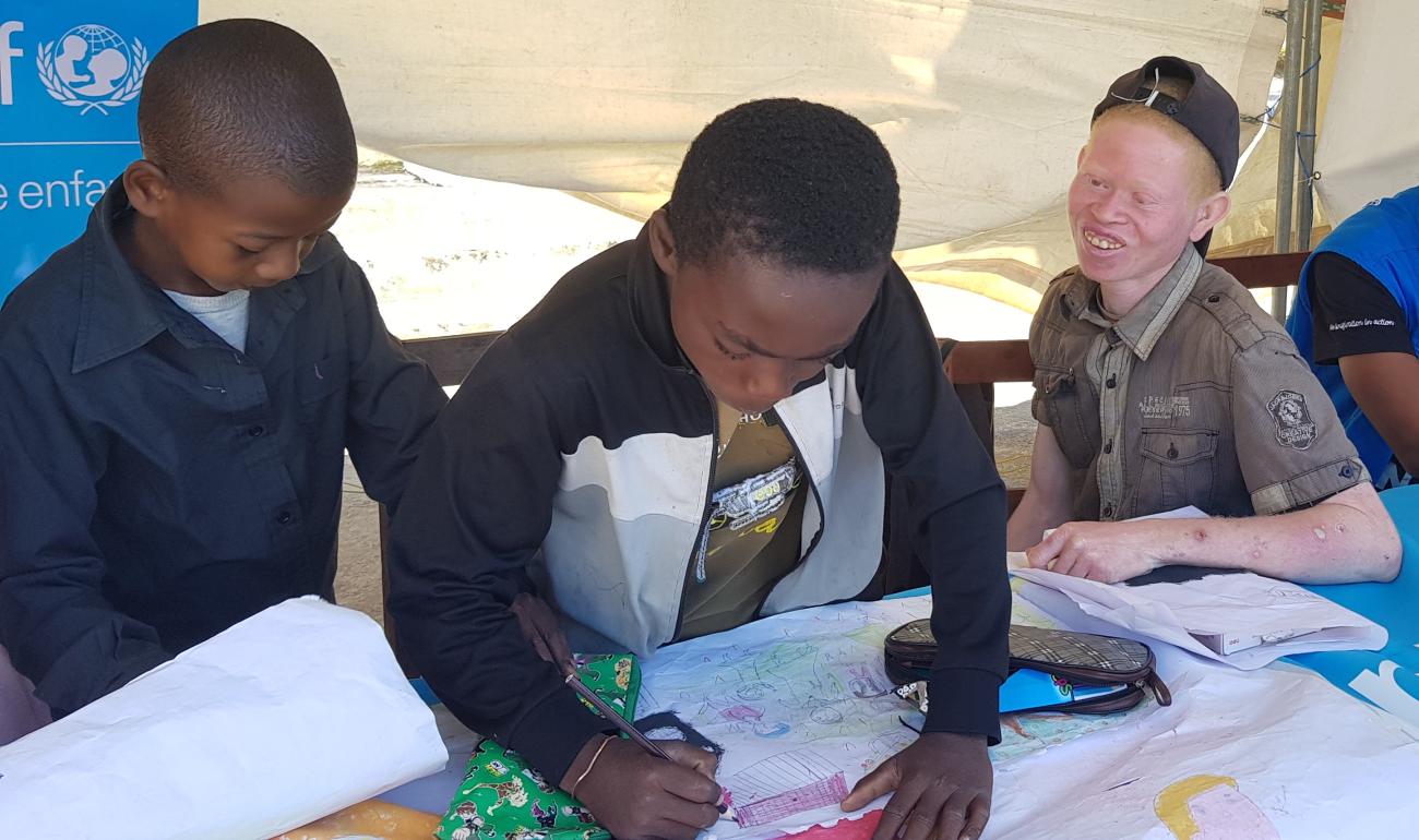 Three children drawing inside a tent