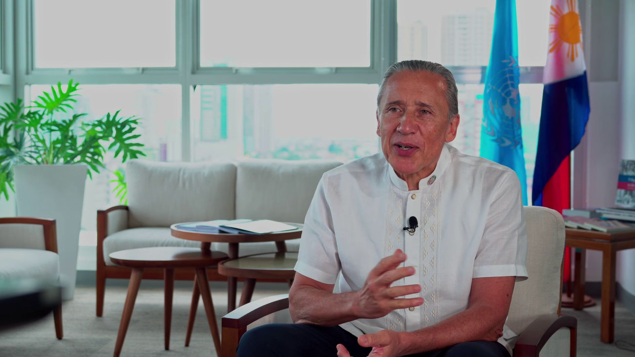 man in white shirt sits down speaking to the camera 