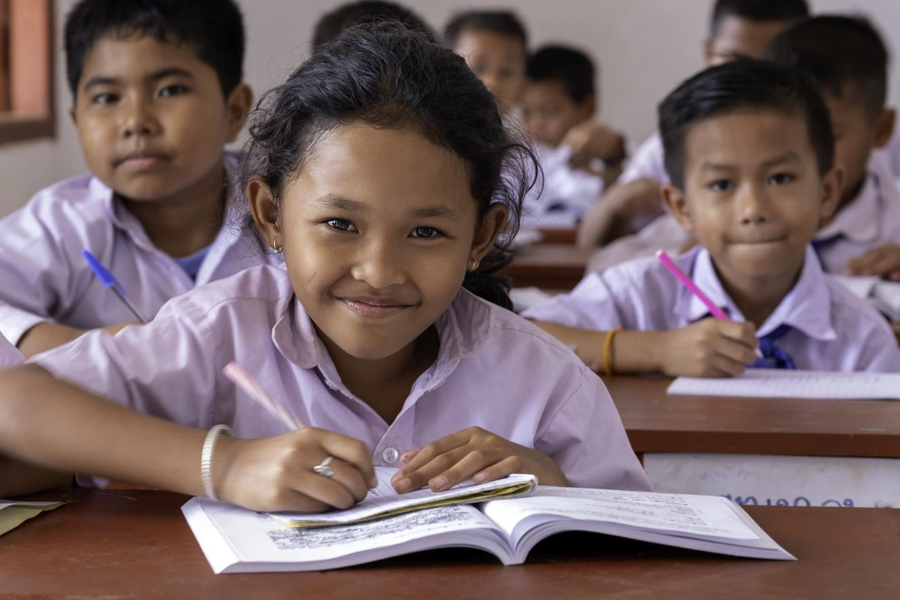 school children sit at their desks working 