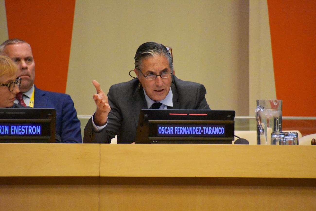 man in dark suit speaking at panel