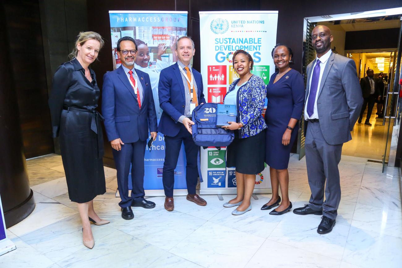 UN officials stand in front of a banner of SDGs and other public health info