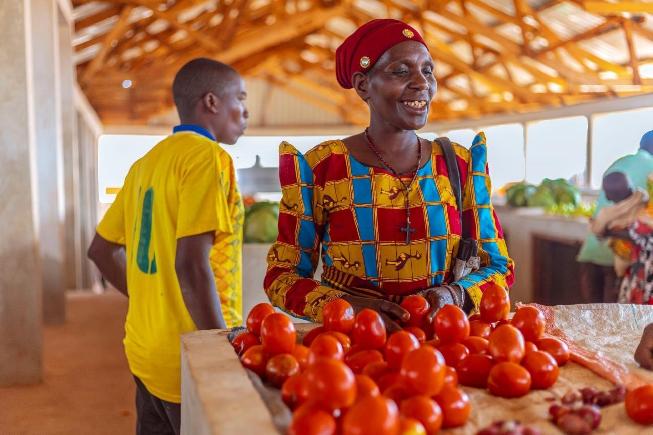 woman stands behind her tomato stand at market