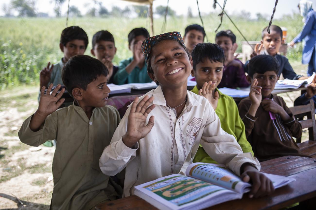 group of young school boys sit in outdoor classroom smiling at camera 