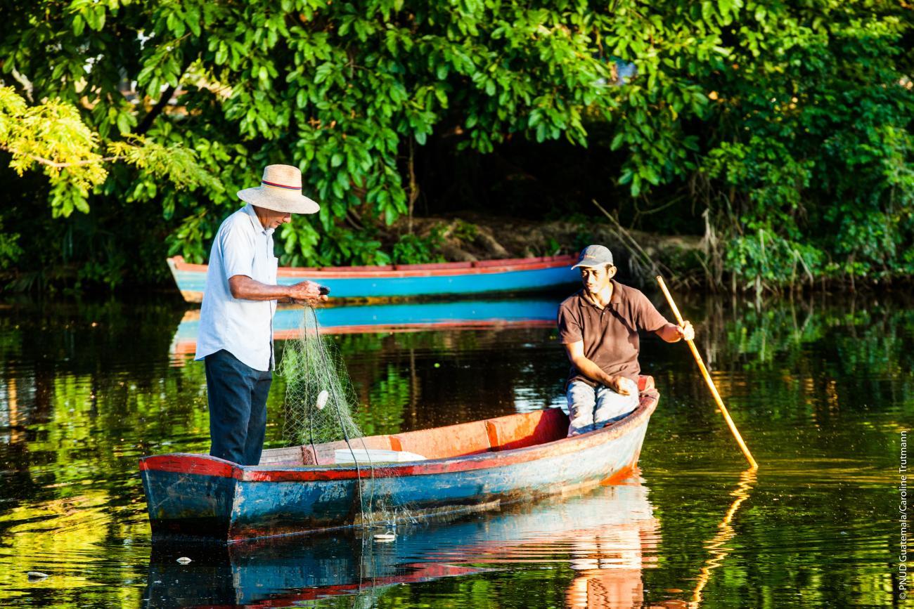 two people on a wooden rowing boat with trees behind them
