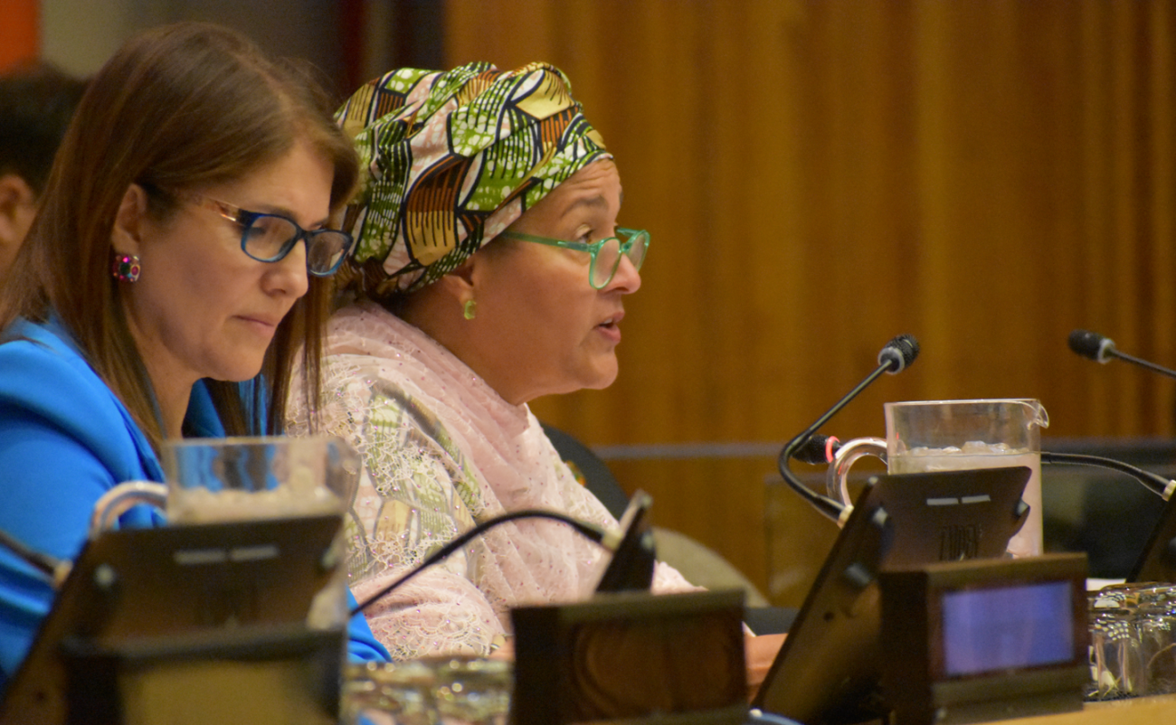 woman in pink top and green head scarf speak at panel discussion 