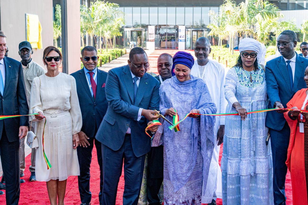 group of people standing in a row on a red carpet cutting the ribbon to inaugurate a new building