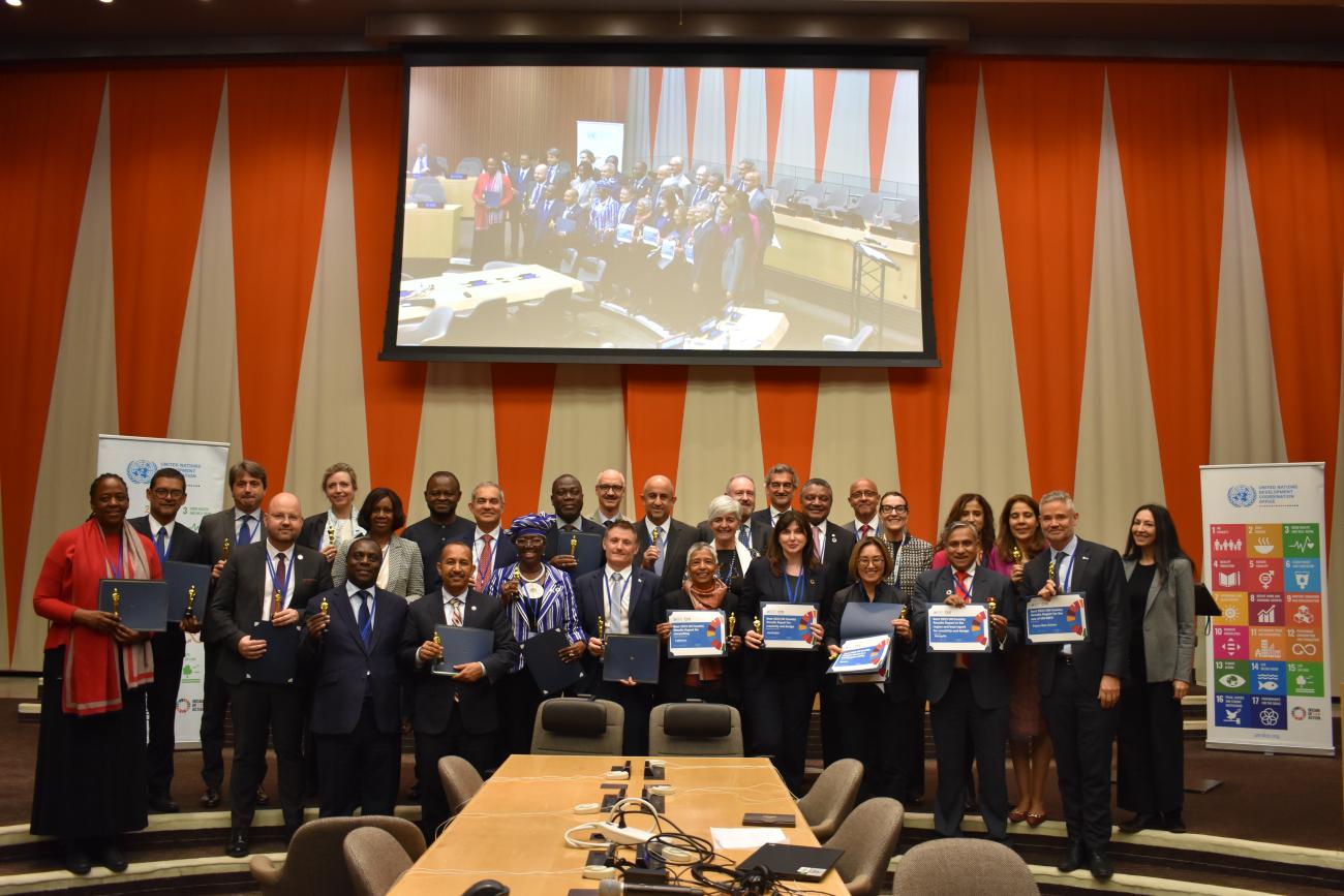 group photo of people standing in meeting meeting room holding on to prizes and looking into the camera