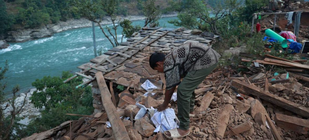 boy sifts through rubble of collapsed building