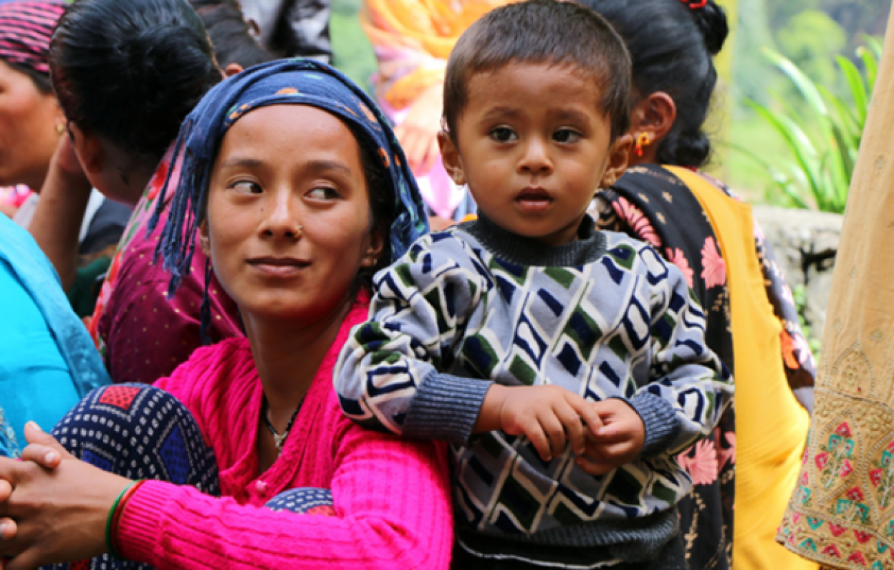 The image shows a group of people outdoors. There is child who is dressed in a striped sweater.