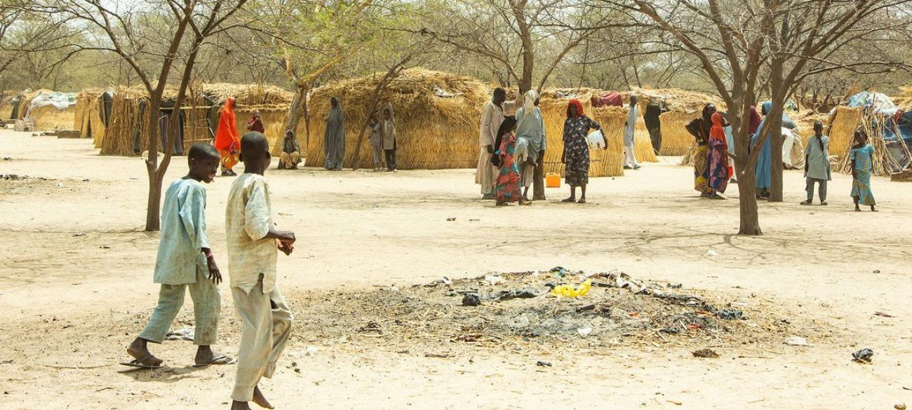 A dessert area with two children walking around in a displaced community