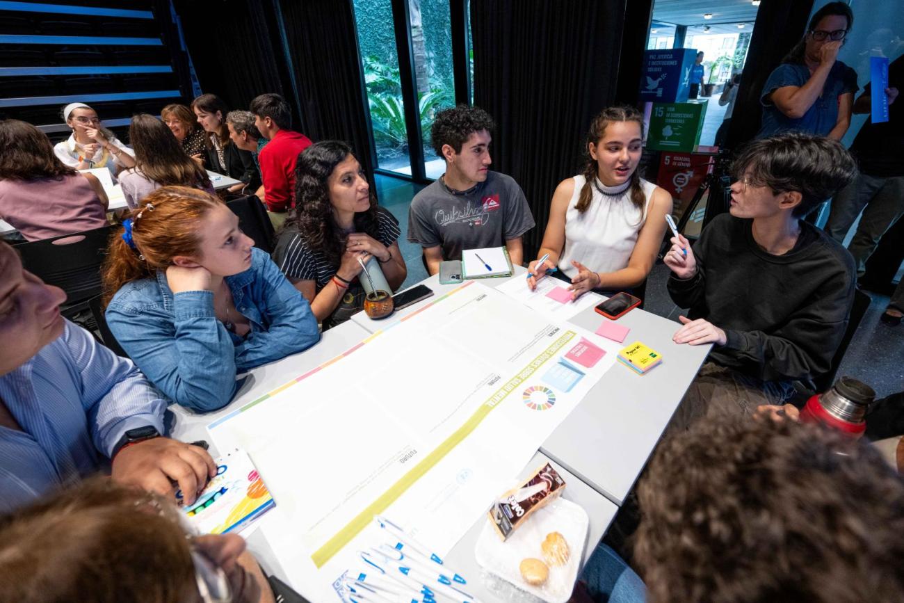 A group of young people seated around a table, engaged in a discussion