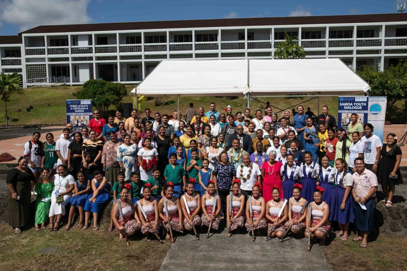 A group of people in an outdoor setting with young people in traditional dress and the UN Secretary-General. 