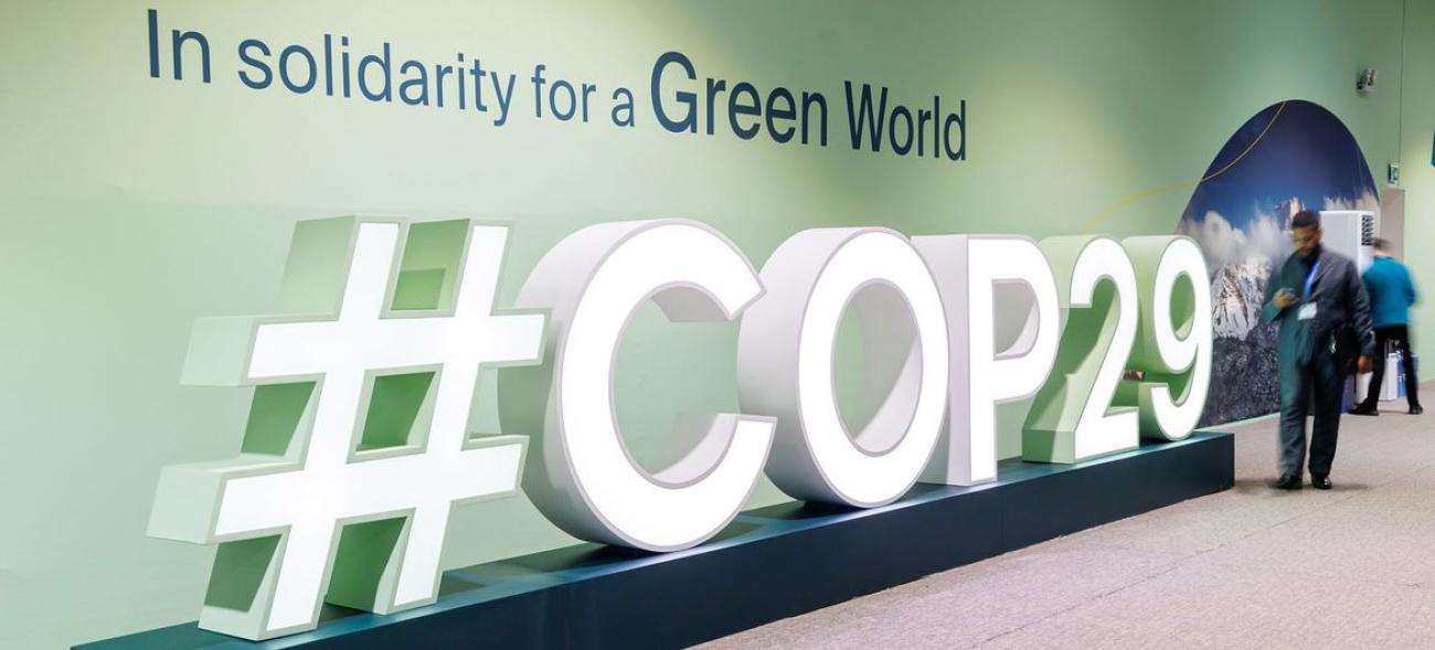 A sign that reads COP29 with a map standing next to it