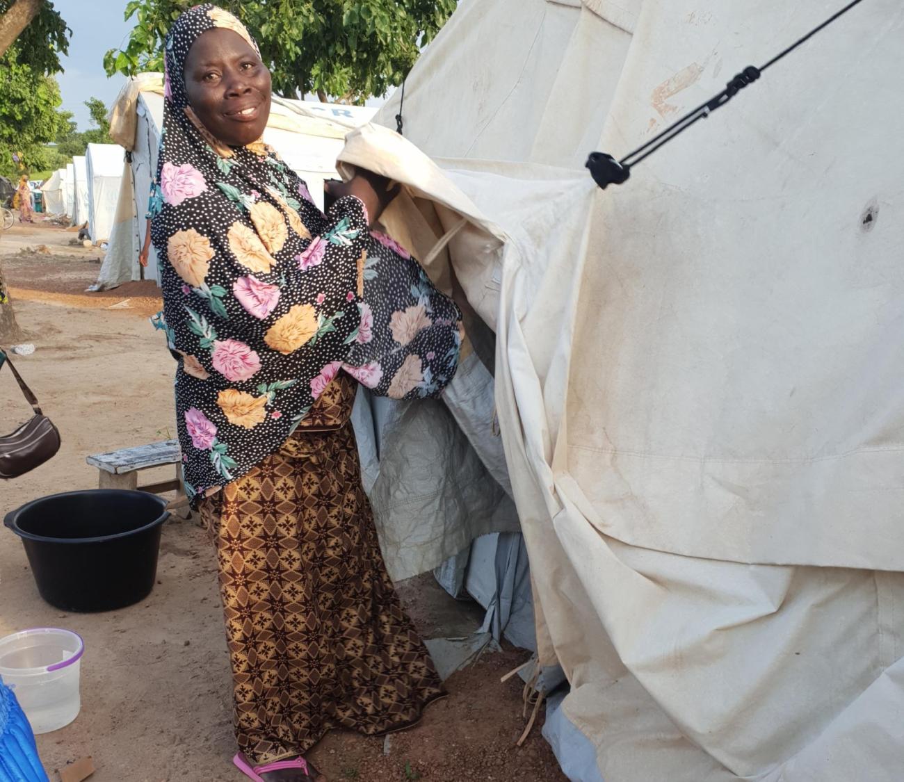 Woman in traditional Ghanaian dress outside temporary housing, demonstrating UN support to displaced populations in Ghana