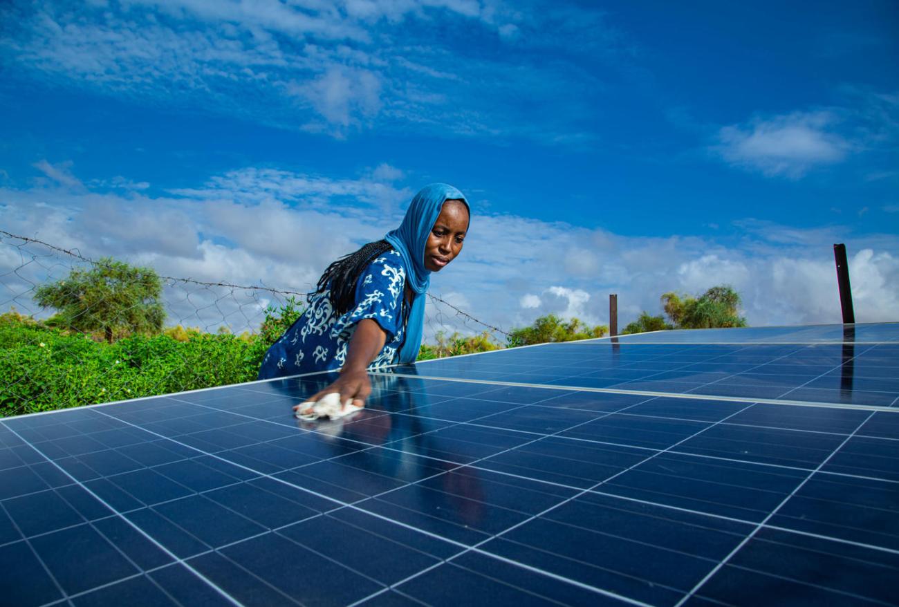 A woman is cleaning a solar panel outdoors