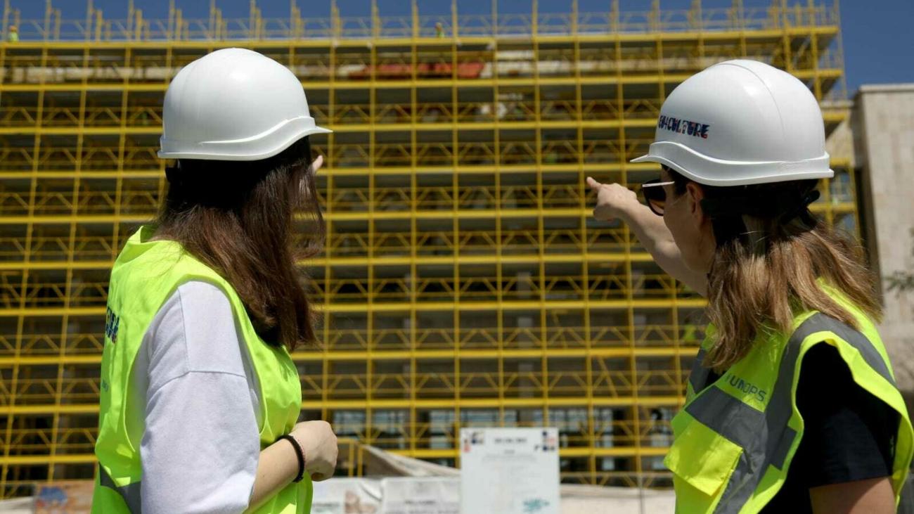 Two women in an outdoor setting pointing at an infrastructure project