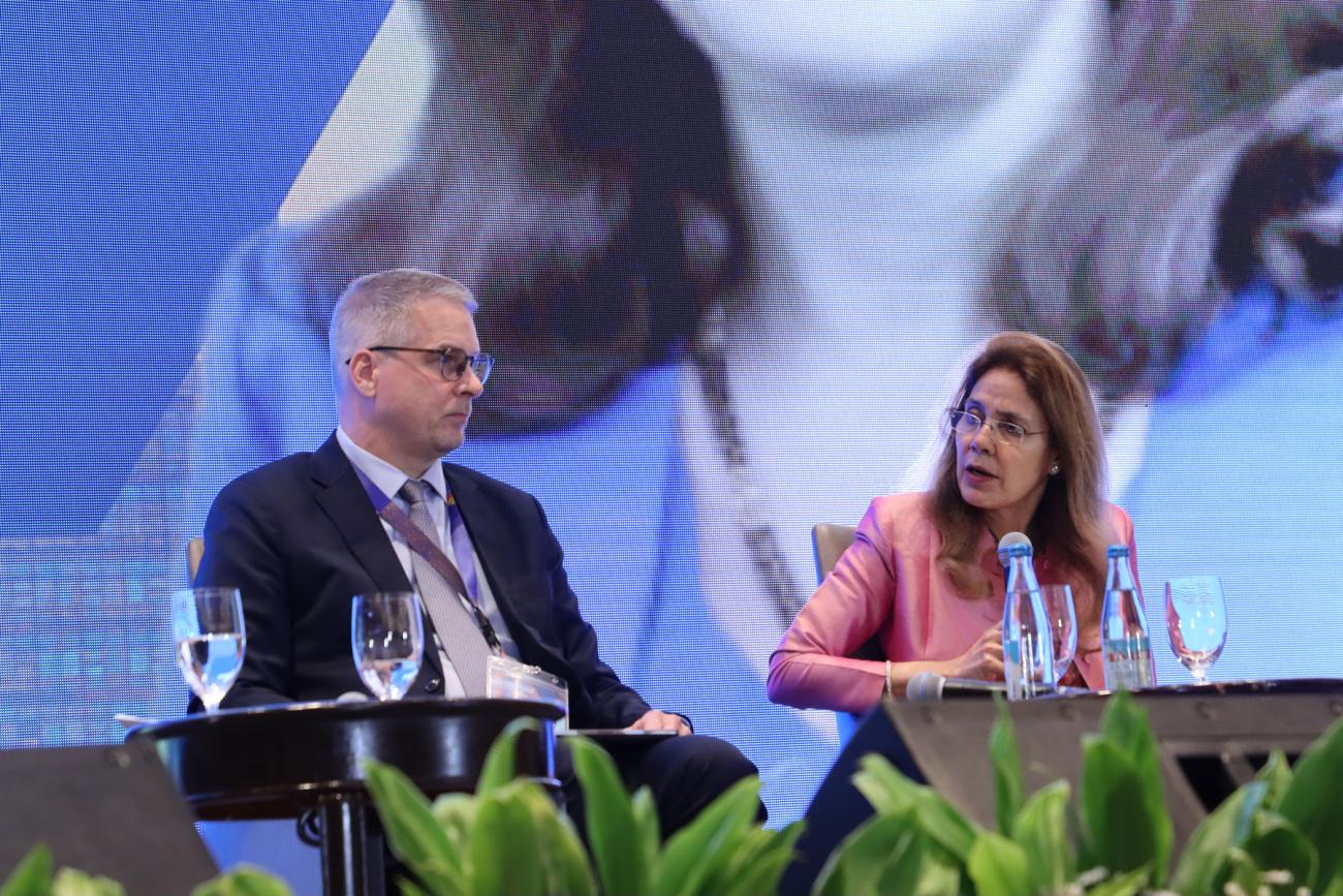 A man and a woman are speaking on a stage.
