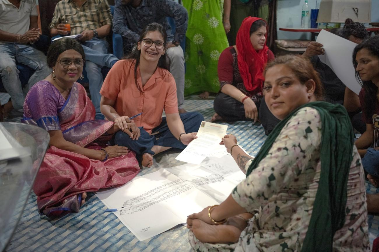 A group of people in an indoor setting congregating around a document